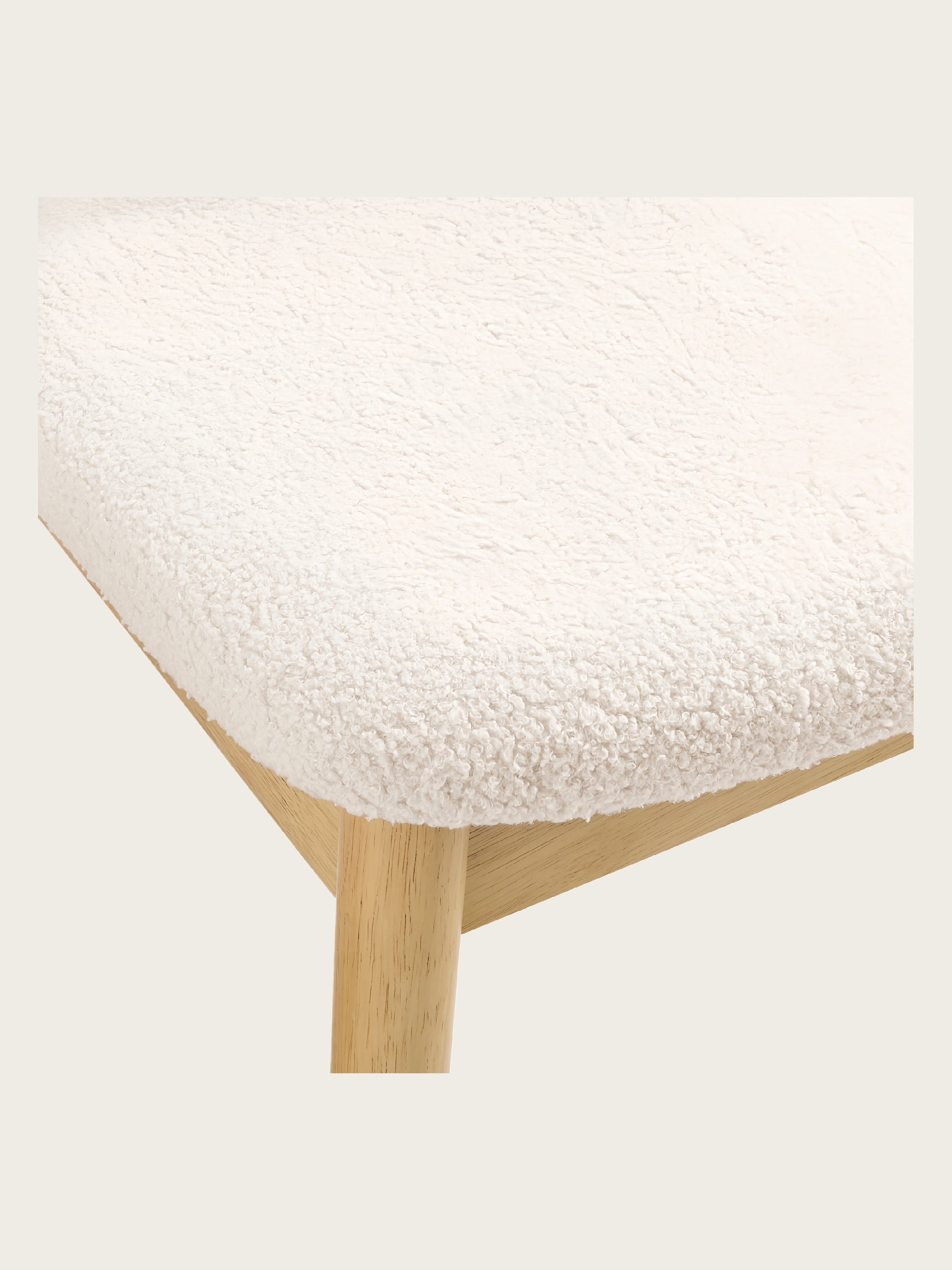 Close-up of Del Mar dining chair seat featuring white teddy boucle upholstery and natural rubberwood leg