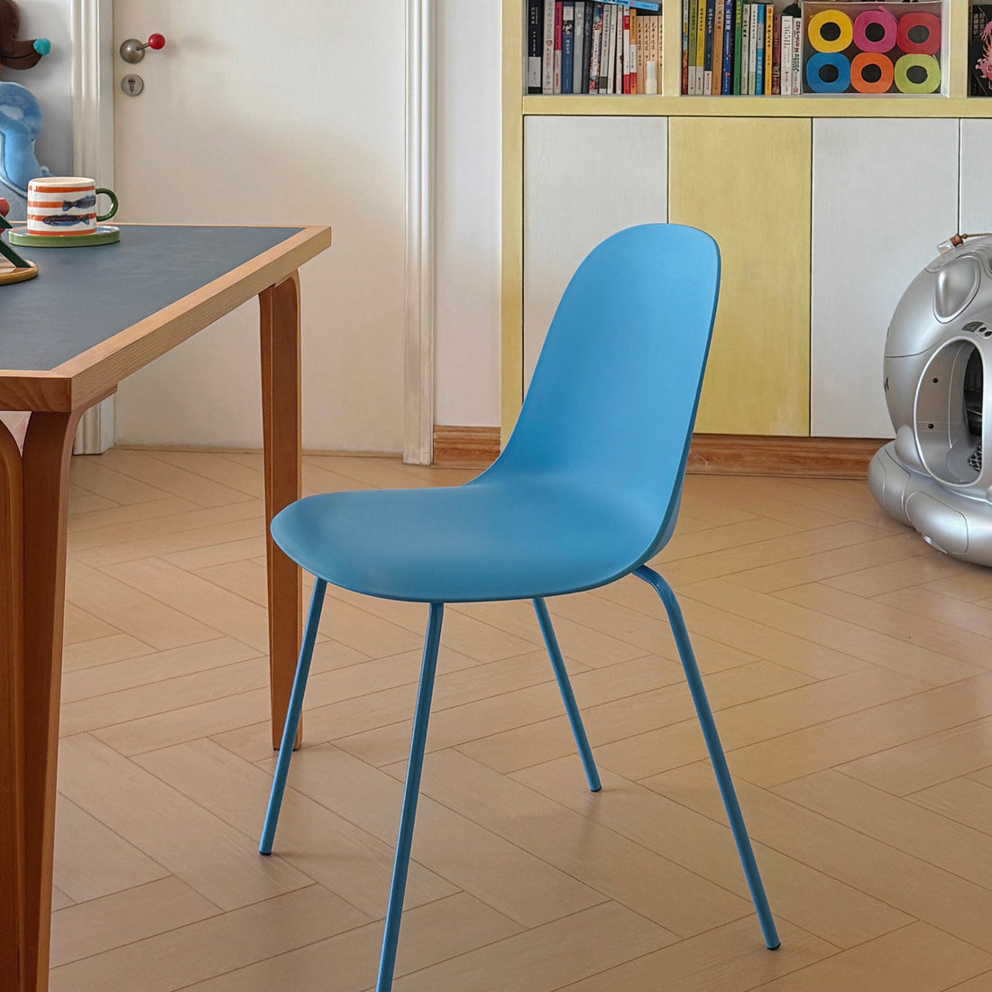 Modern blue plastic dining chair with metal legs in an apartment